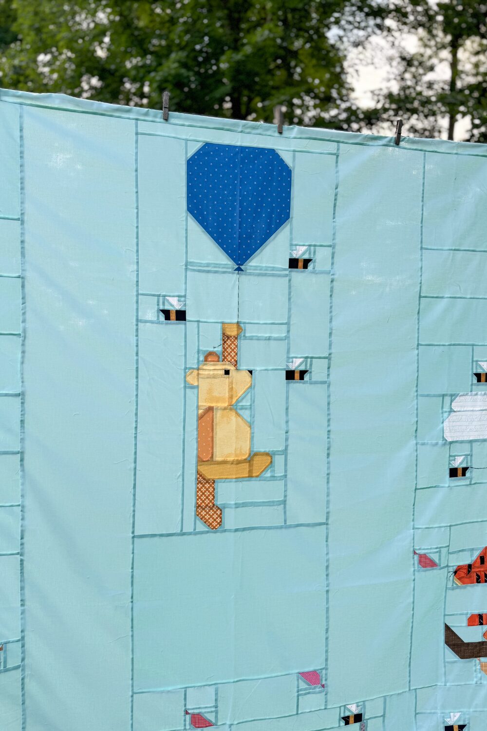 Close-up of Winnie the Pooh quilt block with dark blue balloon on the light blue 100 Acre Wood quilt background.