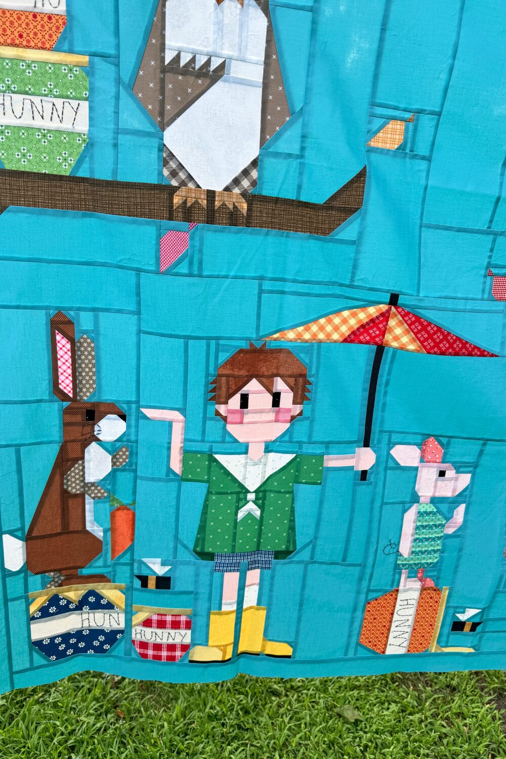 Close-up of Rabbit, Christopher Robin, and Piglet quilt blocks in the finished 100 Acre Wood quilt top.