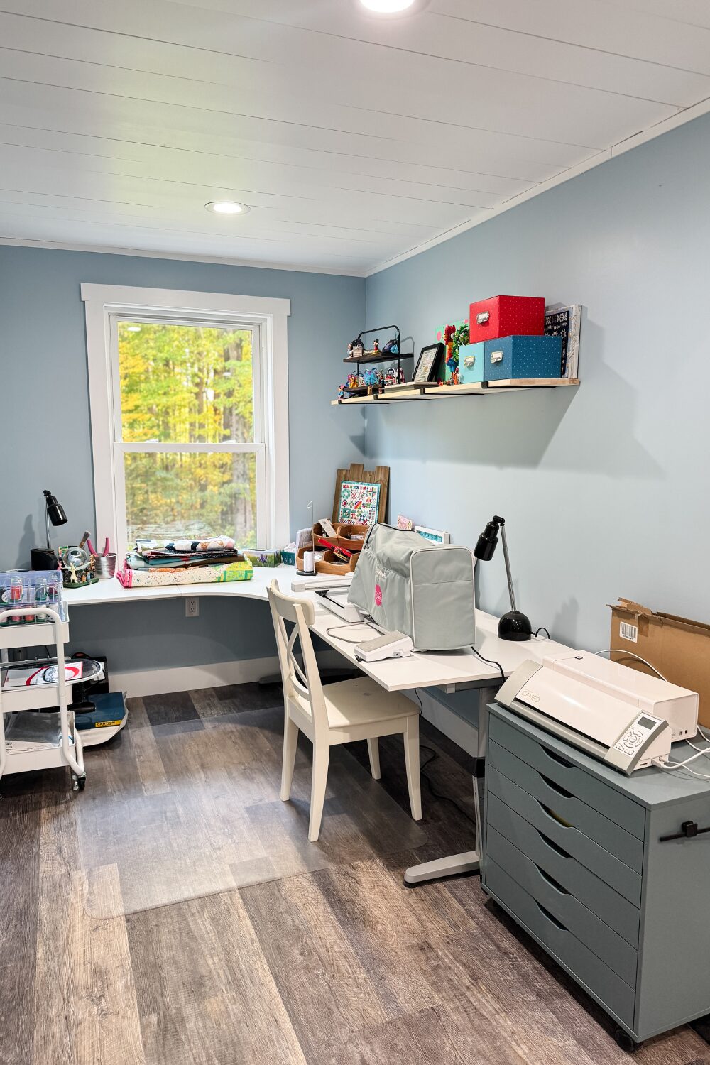 Bernina embroidery machine on an L-shaped desk with organized embroidery supplies.