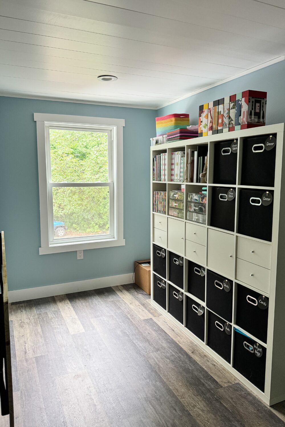 IKEA cube shelf storing craft supplies next to a fold-down wall-mounted work counter.