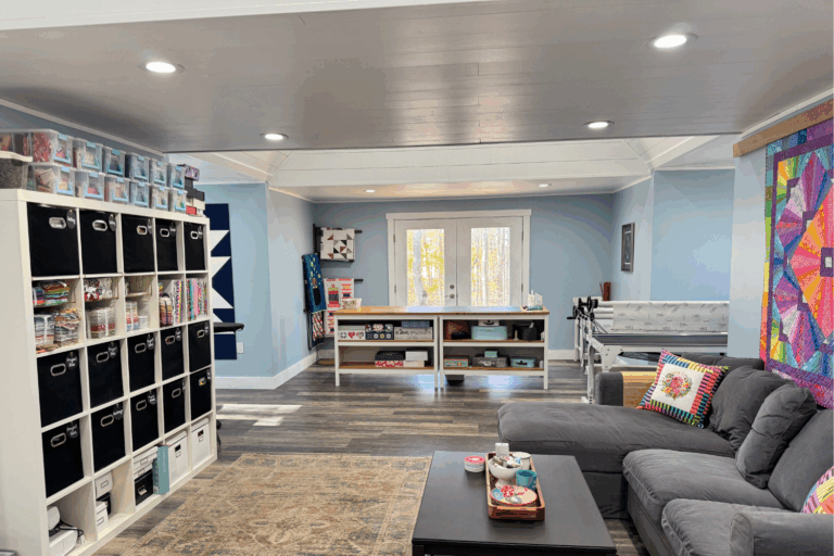 Wide-angle view of a large quilt studio with French doors, multiple dormer work zones, and ample natural light.