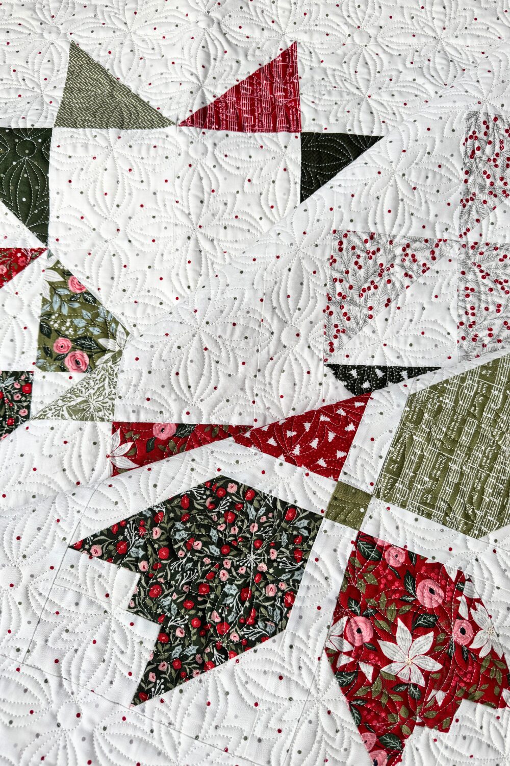 Stylized photo of the Jolly Bar 5 sampler quilt folded to show fabric layers and block colors.