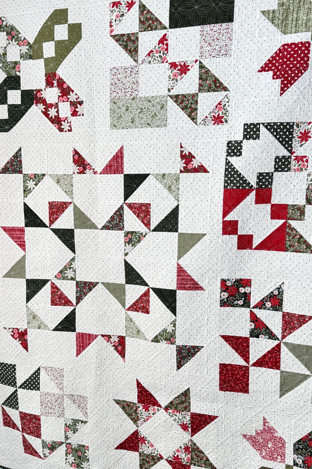 Close-up of multiple quilt blocks showing quilting detail on the finished Jolly Bar 5 sampler quilt.