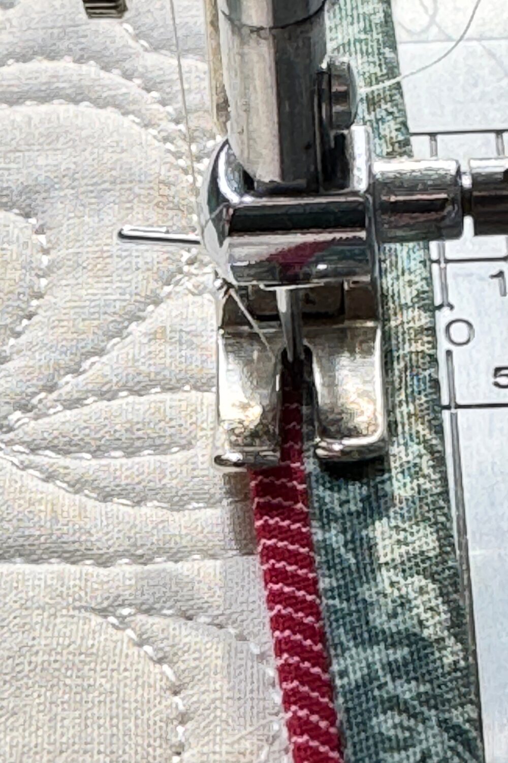 Sewing along the seam line between the flange and binding to secure the binding on the front of the quilt.