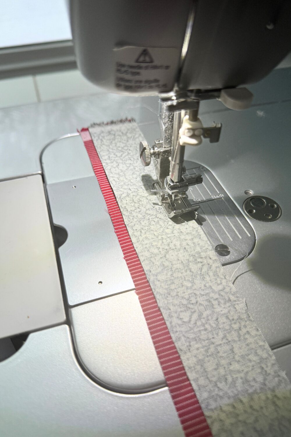 Main binding strip and flange strip sewn together along the long edge to create flanged binding.