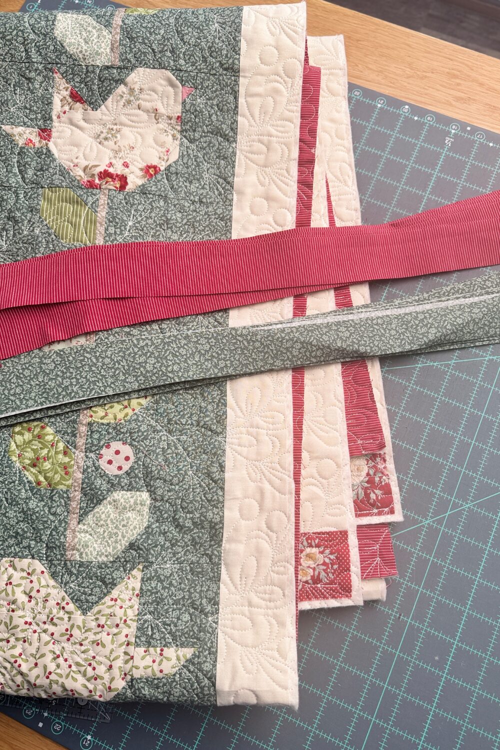 Finished quilt next to two fabrics chosen for flanged binding, showing the main binding fabric and accent flange fabric.