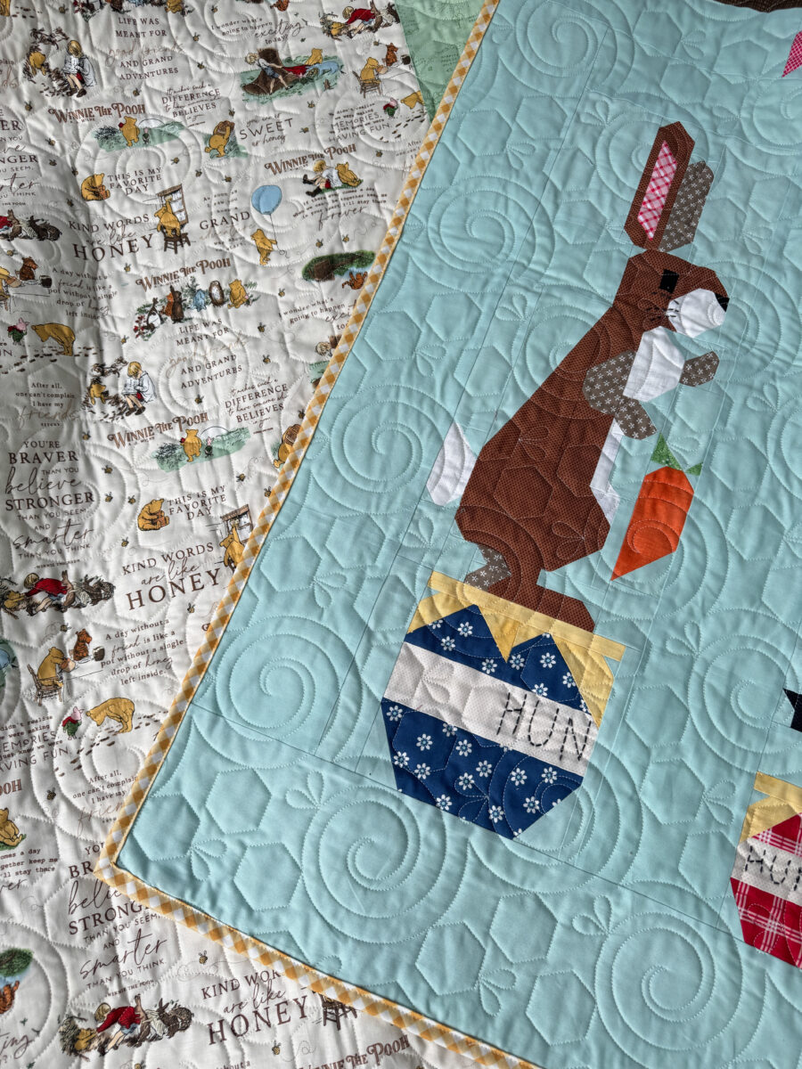Rabbit quilt block folded back to show the backing on the finished Winnie the Pooh quilt.