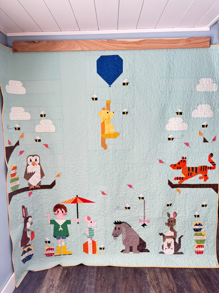 Full view of large Winnie the Pooh quilt hanging on the wall.