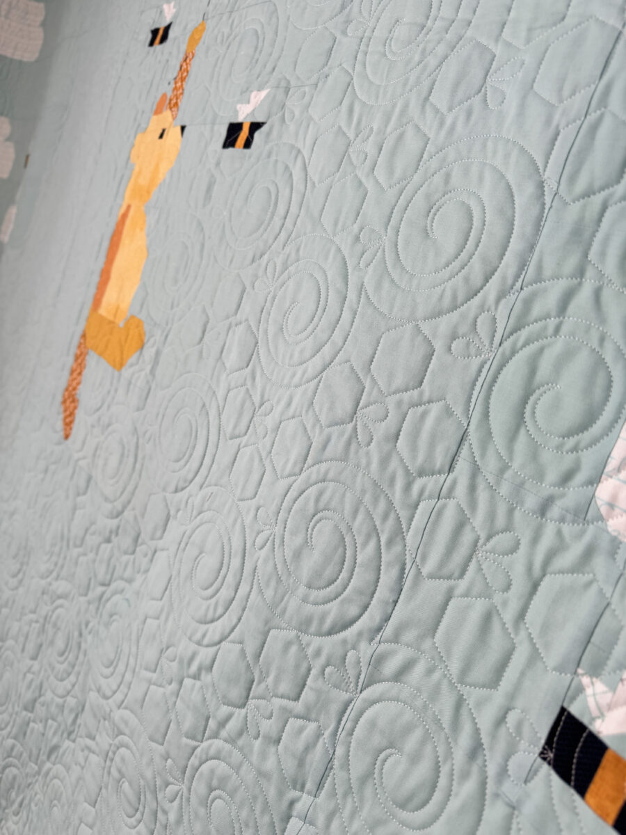 Close-up of longarm quilting detail near Winnie the Pooh quilt block.