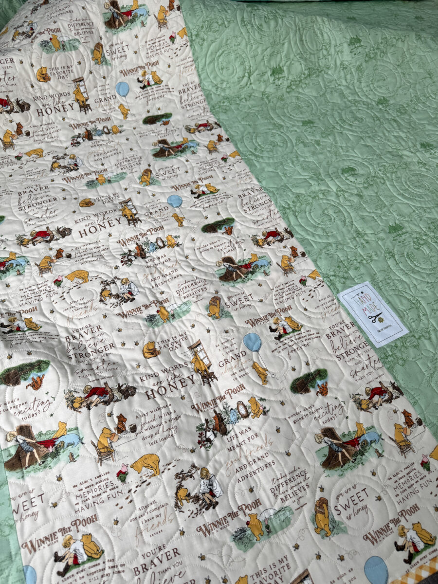 Back of Winnie the Pooh quilt showing pieced backing and longarm quilting.
