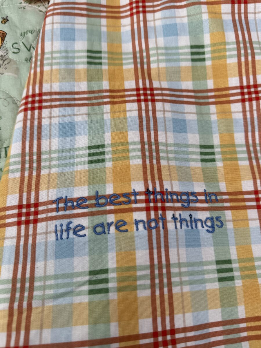 Close up of embroidered quote inside quilt coat reading The Best Things in Life aren't things.