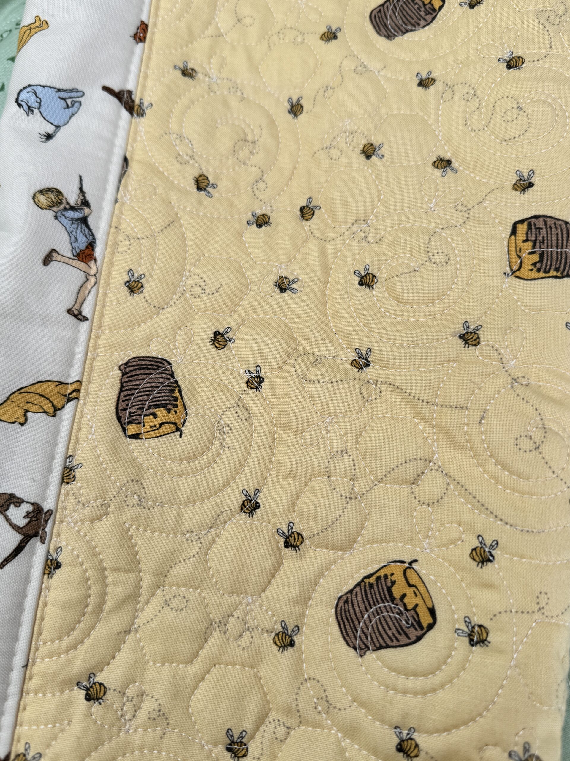 Close up of yellow honeypot and bees fabric with honeycomb pantograph quilting.