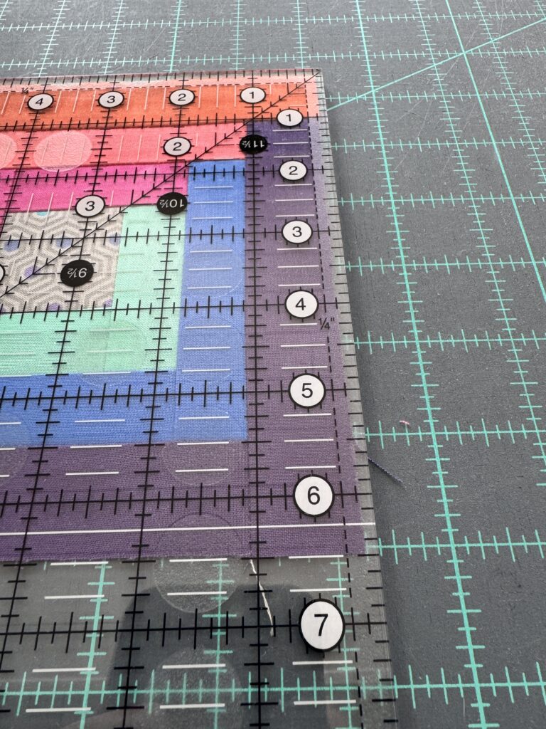 A log cabin block under a ruler showing it to be 1/8 inch too small