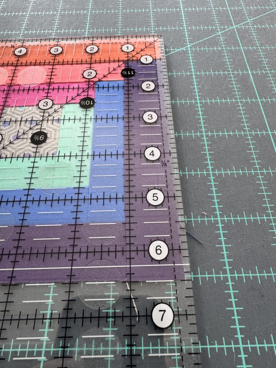A log cabin block under a ruler showing it to be 1/8 inch too small