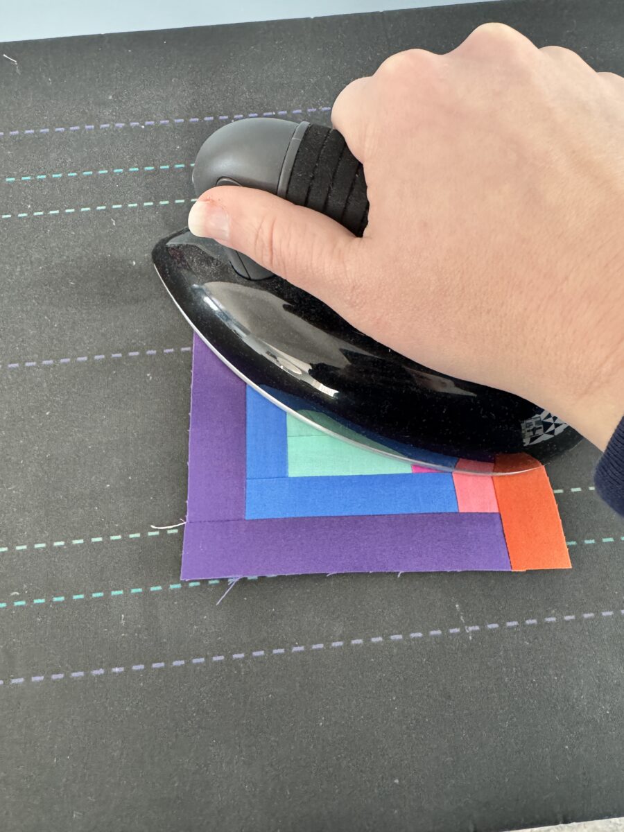 Pressing the Log Cabin quilt block with an iron pressing straight down to not distort the block