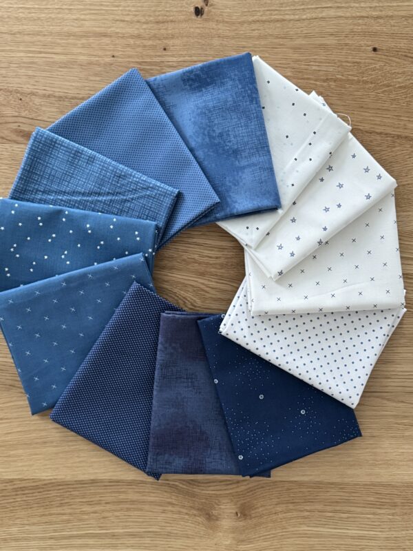 Snowbound Seasonal Basics 12 piece fat quarter bundle fanned in a circle with blue, denim, navy, and white Riley Blake Basics