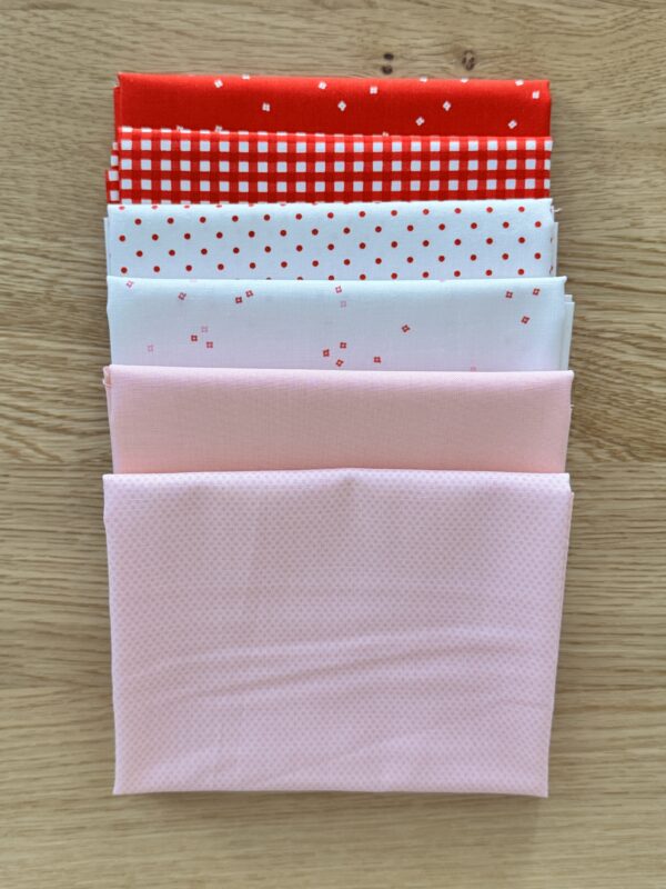 Hugs Seasonal Basics Petite fat quarter bundle laid in one row with red and pink Riley Blake Basics