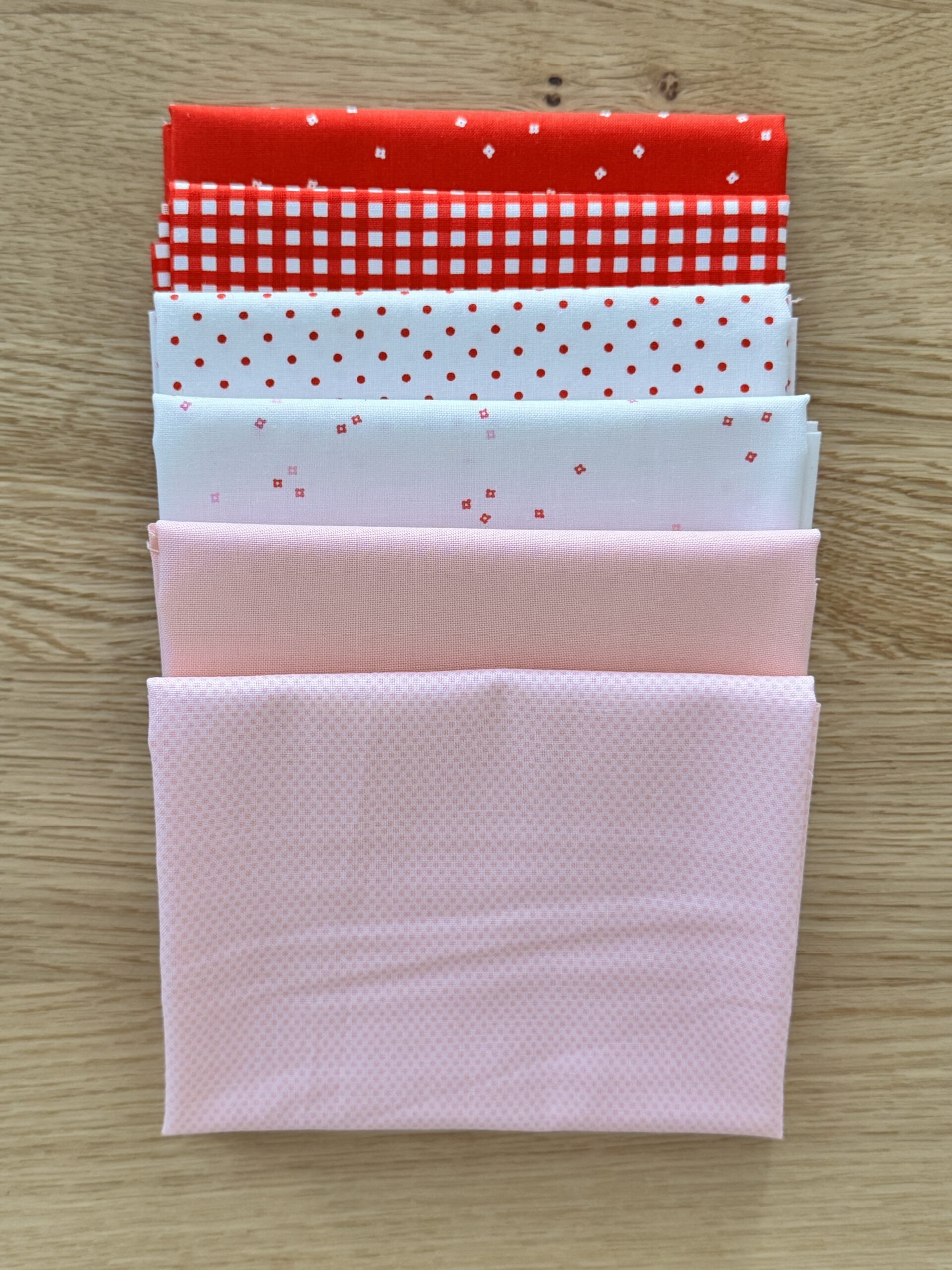 Hugs Seasonal Basics Petite fat quarter bundle laid in one row with red and pink Riley Blake Basics