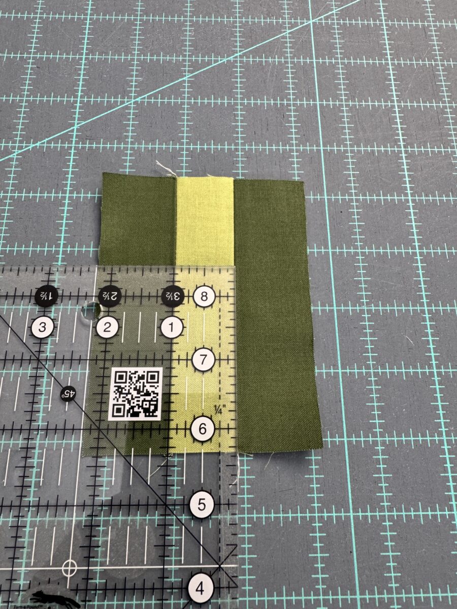 Using 1.5 inch strips of fabric sewn together to test the accurate quarter inch seam. Laying a ruler on the center piece shows a perfect 1 inch strip.