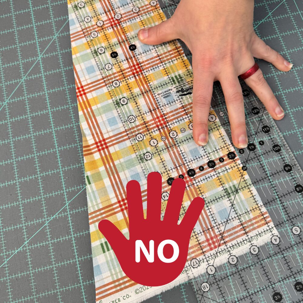 Improper hand positioning on a quilting ruler. Hand is shown on the edge farthest from the cutting edge.