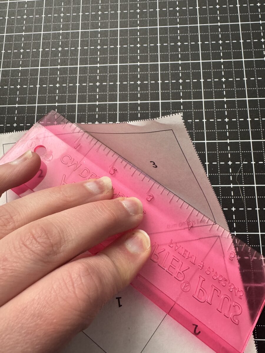 Using an add a quarter ruler to fold back foundation paper before trimming for flying geese
