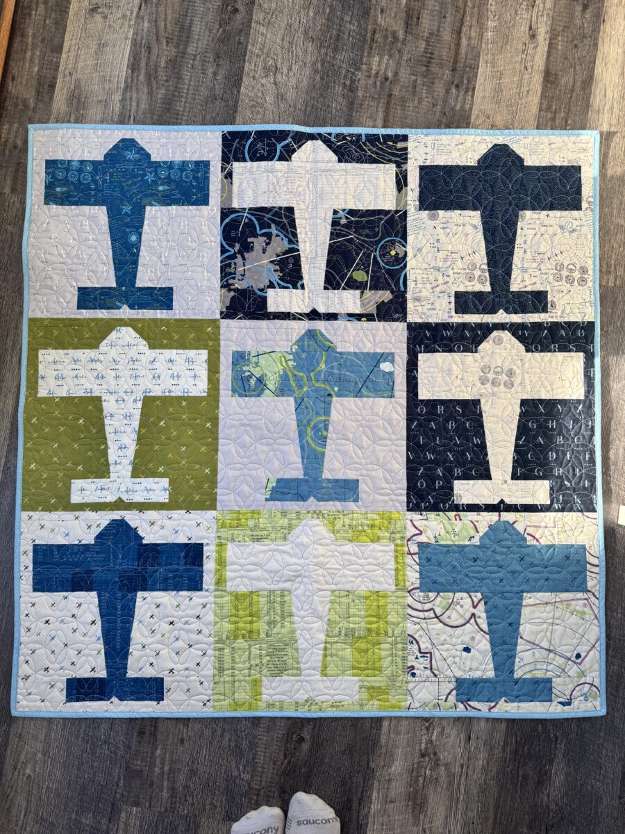 Aviator baby quilt made with High Flight fabric featuring nine airplane blocks in a 3x3 layout