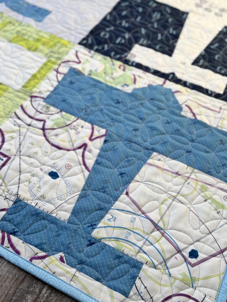 Close-up angled view of blue airplane quilt block from Aviator pattern made with High Flight fabric