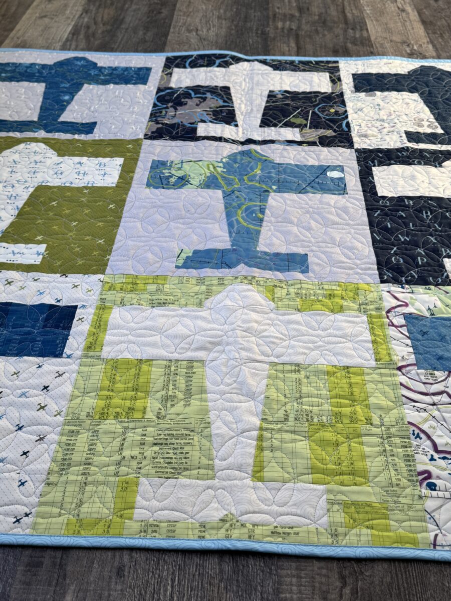 Angled upward view of Aviator baby quilt showing airplane blocks and light blue binding