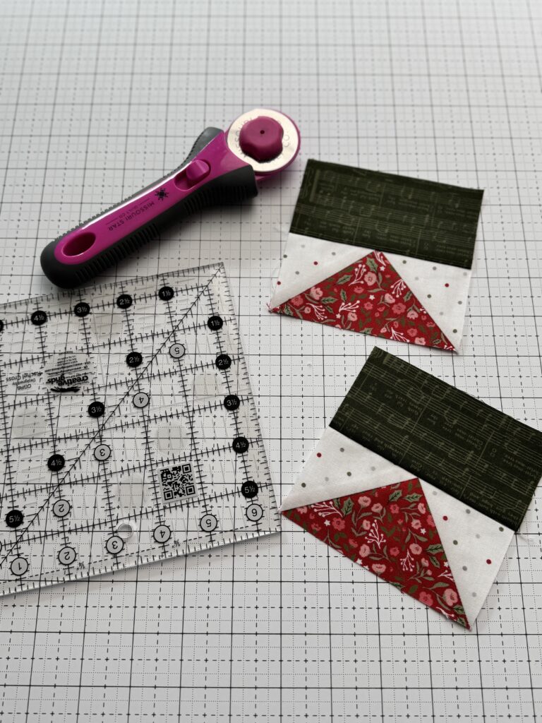 Two flying geese units side by side with ruler and rotary cutter showing accurate and inaccurate seam allowance results