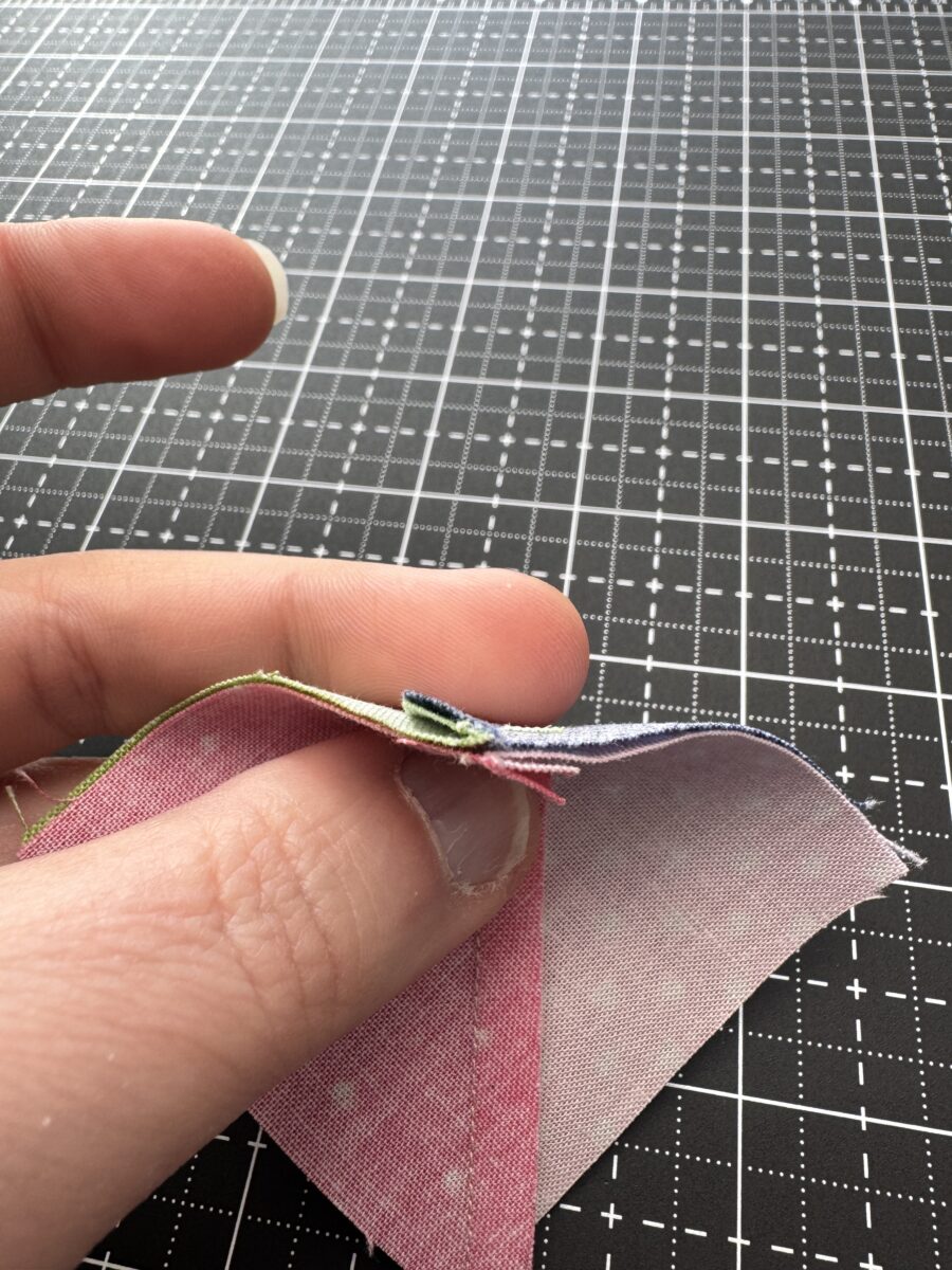 Two half square triangle units placed right sides together with seams pressed in opposite directions to nest