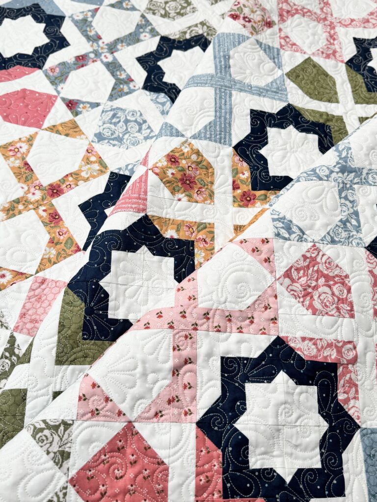 Dreamer quilt folded in thirds showing geometric design and navy binding detail.