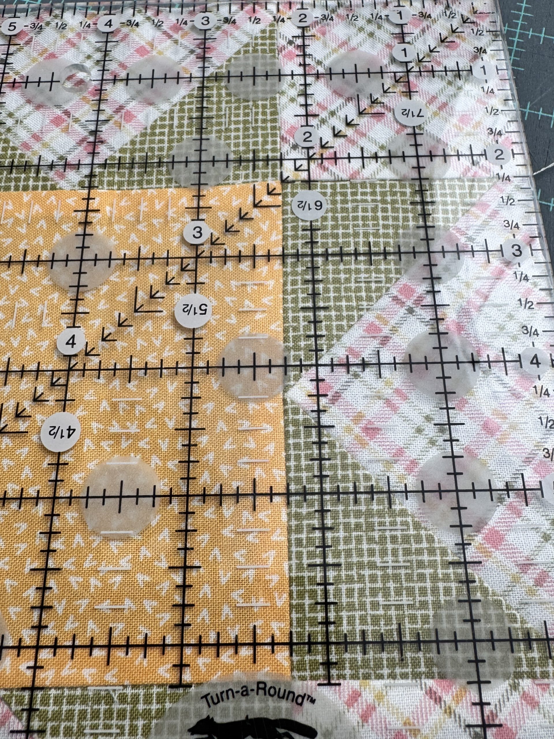 The 2 1/4 inch measurement on the quilting ruler is aligned with the long seam between the flying geese unit and the center square to facilitate squaring up the whole quilt block