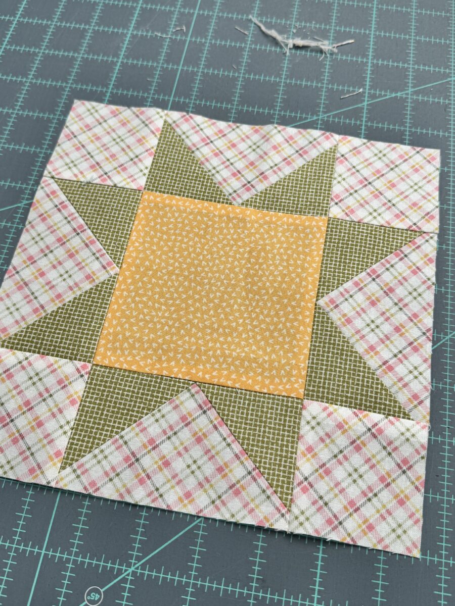 A squared up quilt block with the excess trimmings off to the side showing just threads and very small amounts of fabric were removed