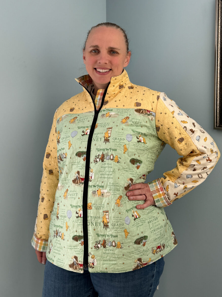 Front view of quilter wearing a handmade Winnie the Pooh Bella quilt coat with black separating zipper.