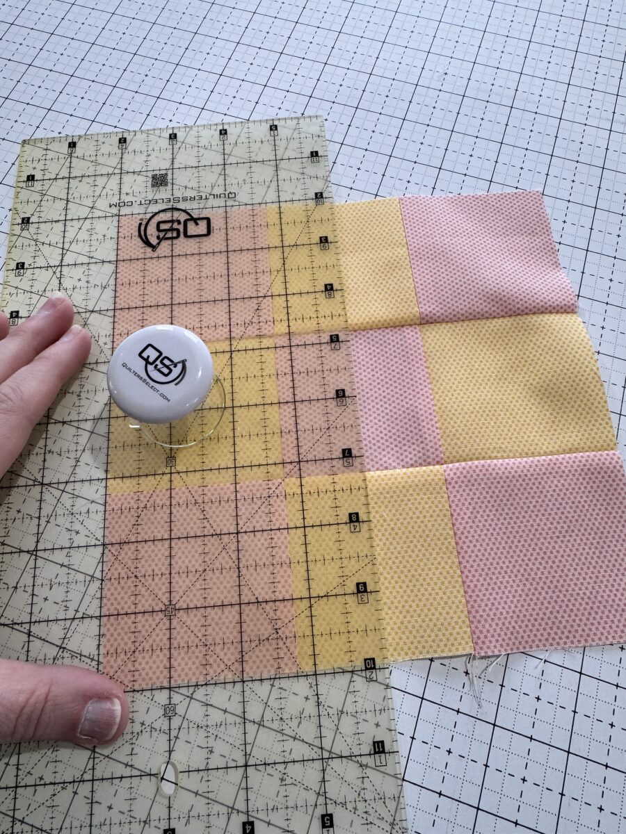 cutting a vertical line to split the 9 patch quilt block in half