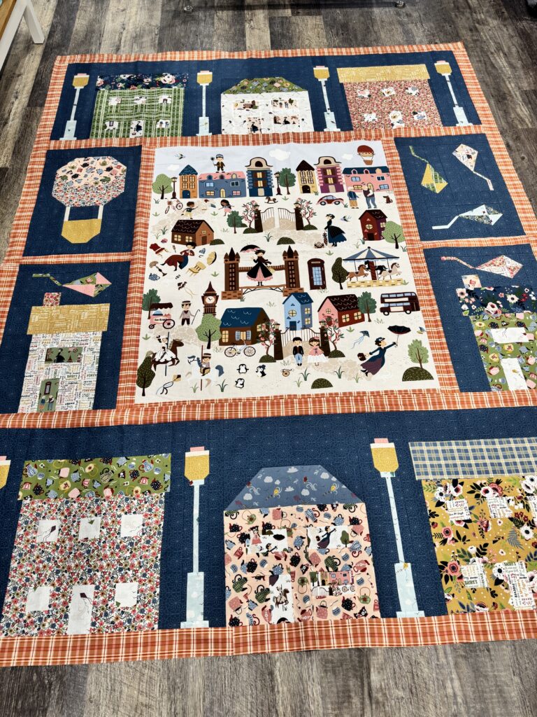 Overhead view of Cherry Tree Lane quilt top after assembly with panel, houses, kites, and sashing