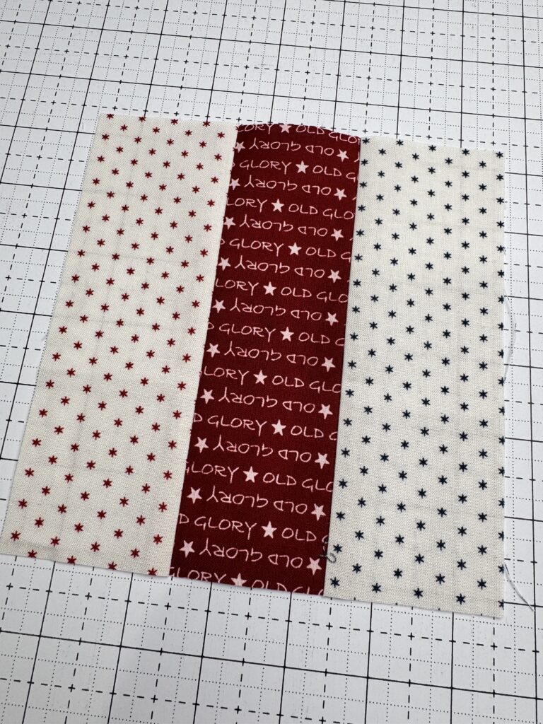 finished rail fence quilt block made with three fabric strips arranged in a simple strip pieced design