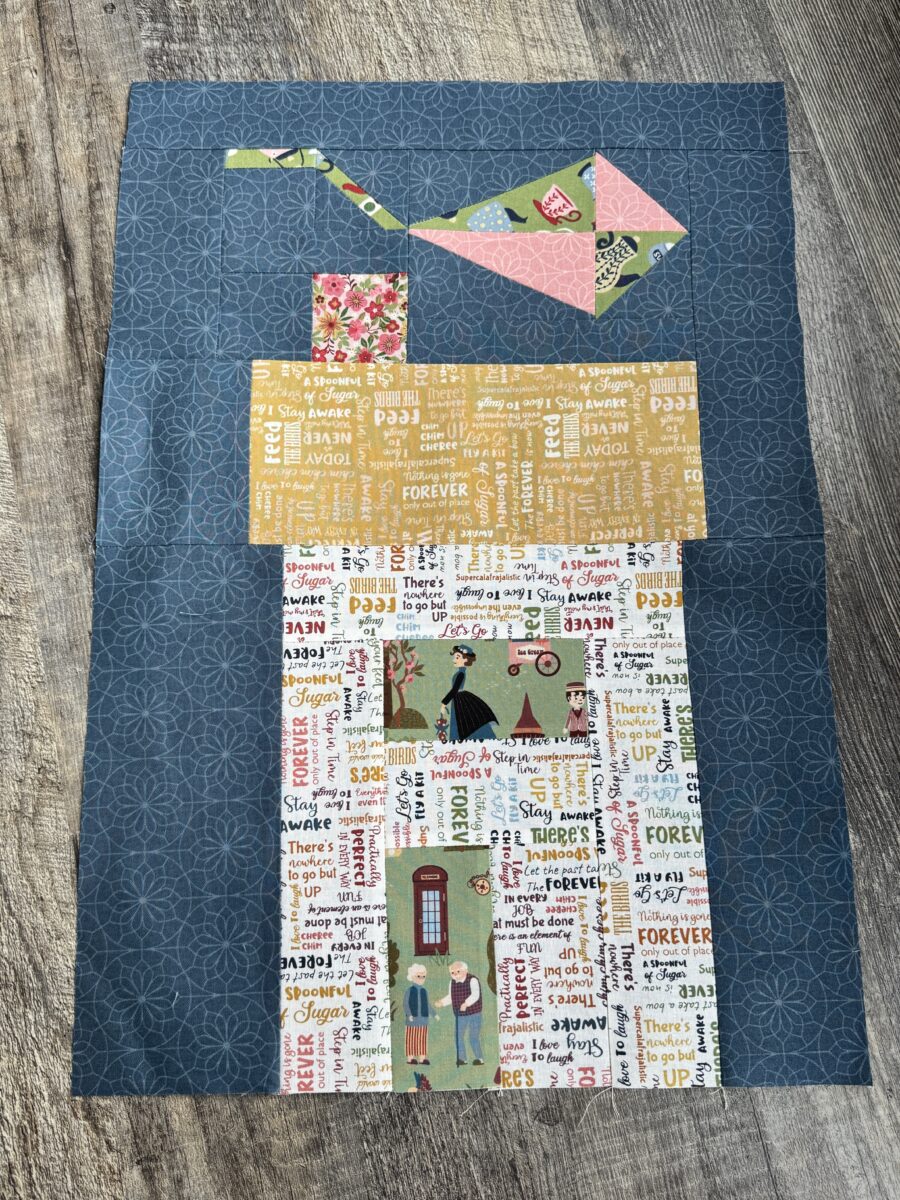 House quilt block with multicolored text fabric, green print window and door, and kite above roof