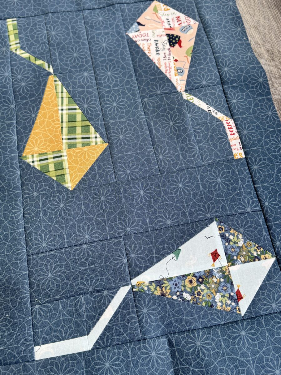 Kite quilt block with three kites flying in different directions made with Spoonful of Sugar fabric
