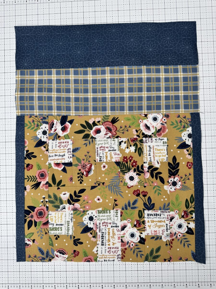 House quilt block with blue plaid roof, yellow floral house, and text print windows and door