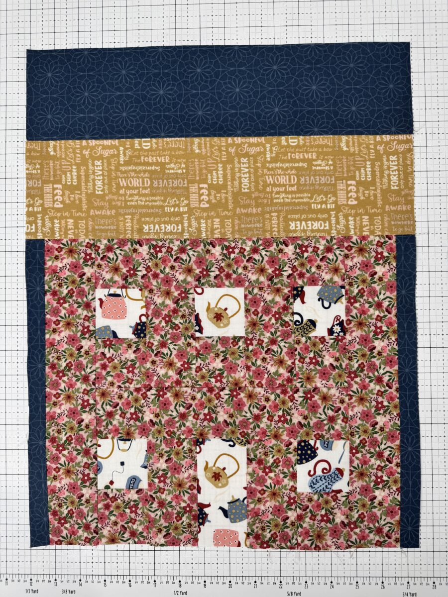 House quilt block with yellow text print roof and pink floral house with teapot windows