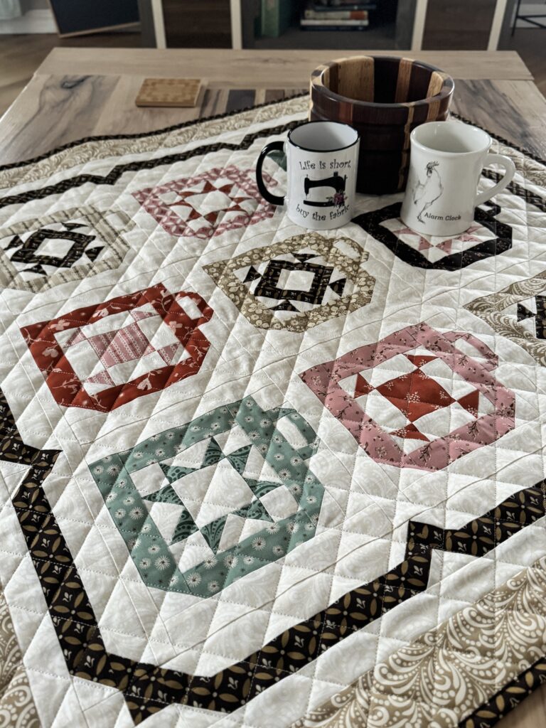 Close view of Mug Collection quilt with pieced coffee mug blocks on a coffee table with coffee mugs
