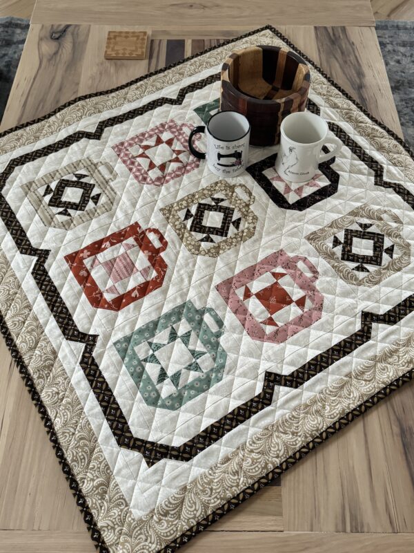 Overhead angle of coffee mug quilt on coffee table styled with mugs and wood bowl