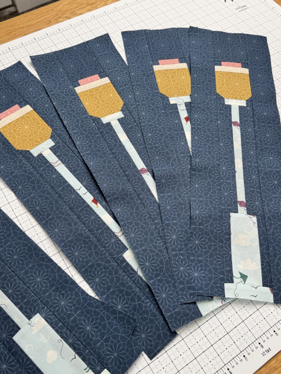 Eight finished lamppost quilt blocks with four fanned out and four stacked