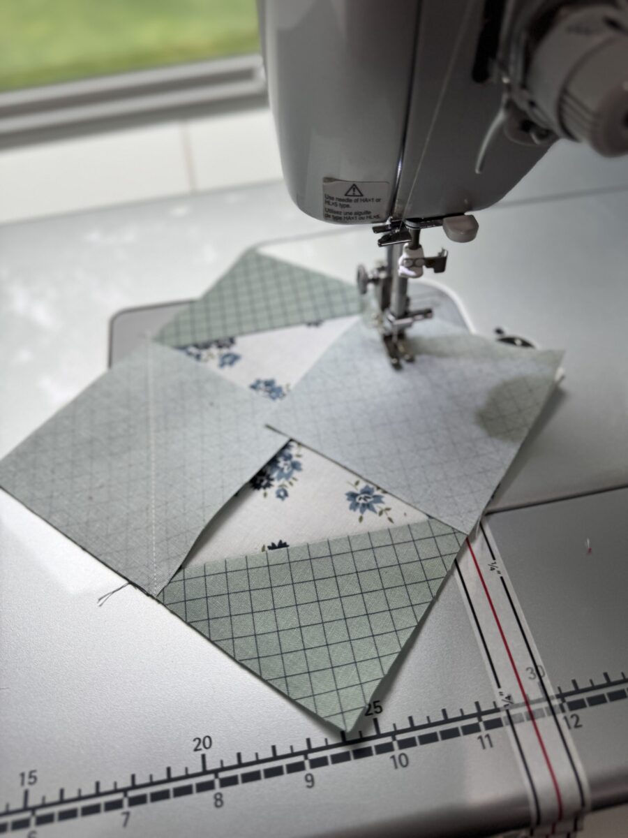 Square-in-a-square quilt block on a sewing machine with the final stitch-and-flip corner being sewn in place