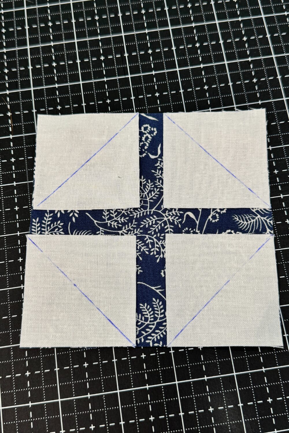 Layout of four corner squares with lines drawn to do a sew and flip technique on the larger square behind to make a snowball quilt block