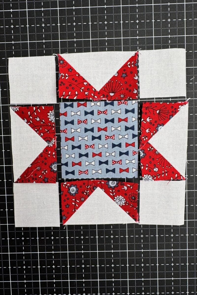 Four corner squares, four flying geese, and a center square arranged in a sawtooth star layout