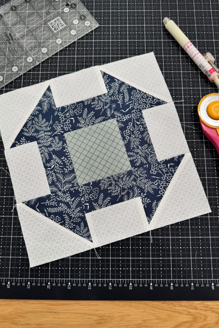 Churn dash quilt block in white, navy, and sage.