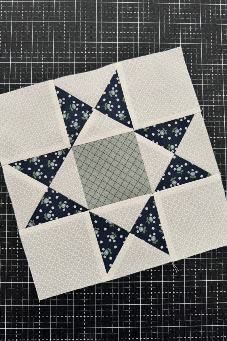 Completed Ohio Star quilt block with hourglass side units and solid squares in the corners and center. Pictured in navy, white, and sage.
