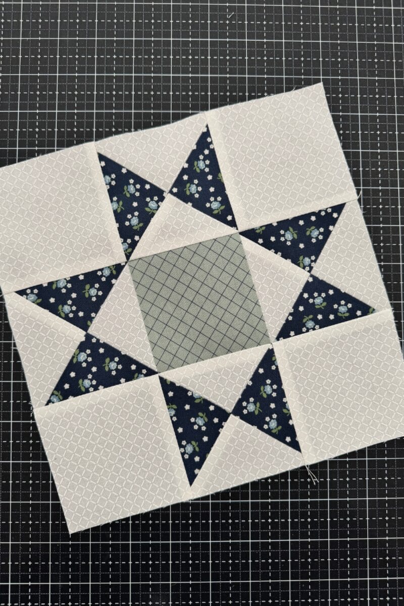 Completed Ohio Star quilt block with hourglass side units and solid squares in the corners and center.  Pictured in navy, white, and sage.  